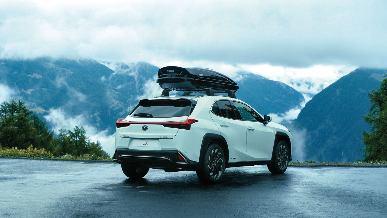 A Lexus UX parked in a mountainous area with a roof box
