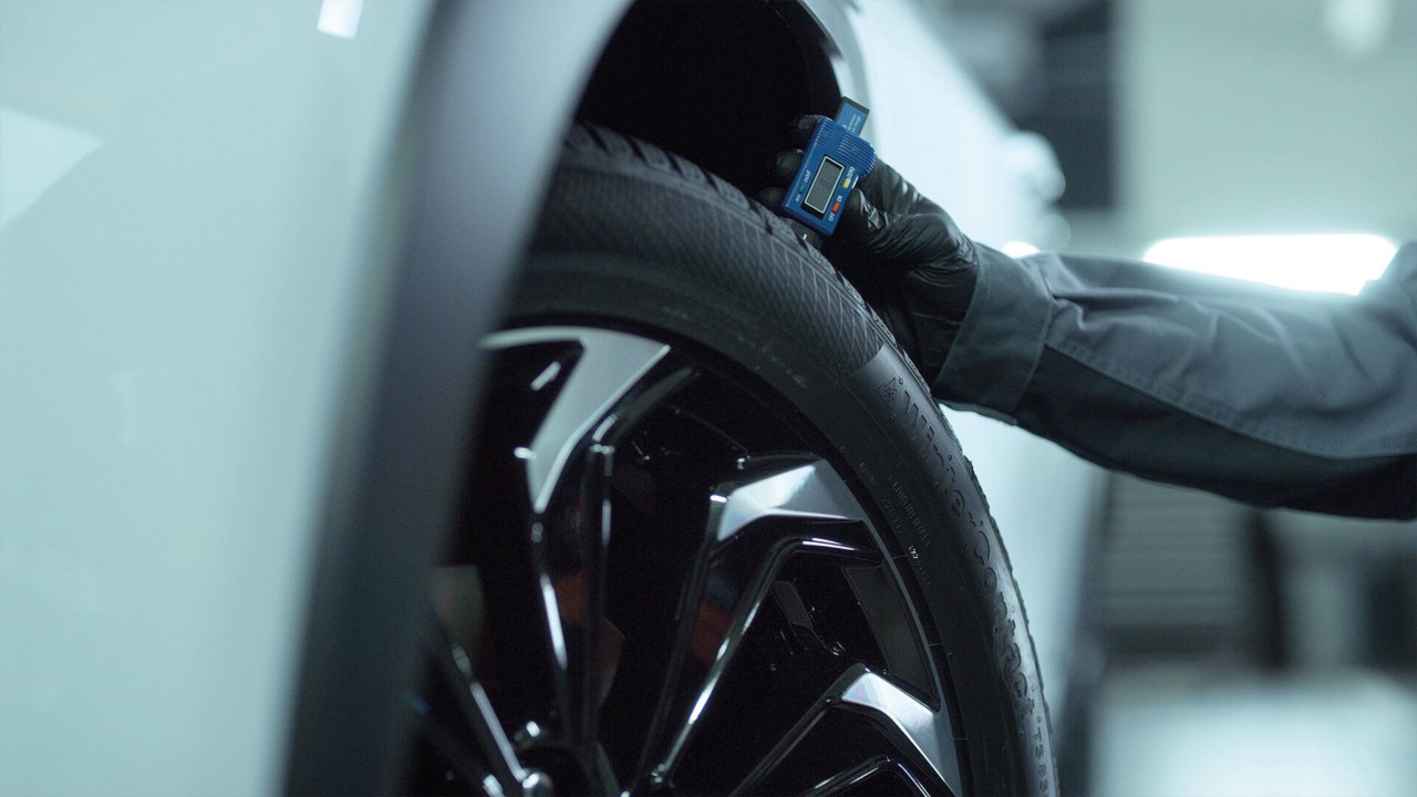 A mechanic checking tyre depth on a Lexus 